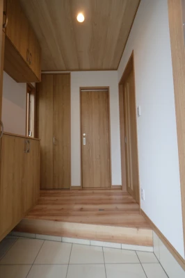 木目柄天井と衣装掛けのある玄関ホール